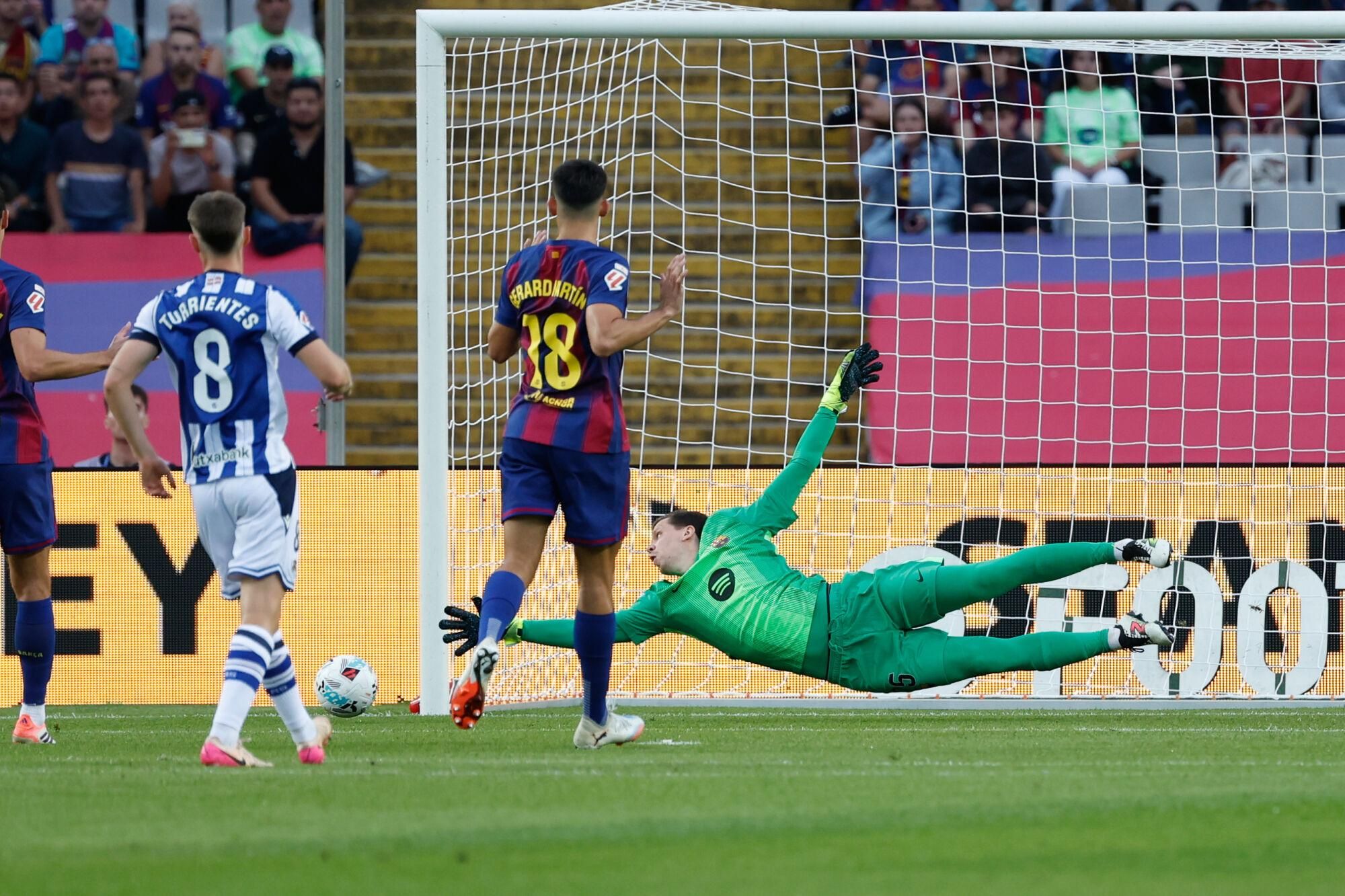 Barcelona's goalkeeper Wojciech Szczesny, bottom, dives for the ball during a Spanish La Liga soccer match between FC Barcelona and Real Sociedad at the Lluis Companys Olympic Stadium in Barcelona, Spain, Sunday, Sept. 28, 2025. (AP Photo/Joan Monfort). EDITORIAL USE ONLY/ONLY ITALY AND SPAIN