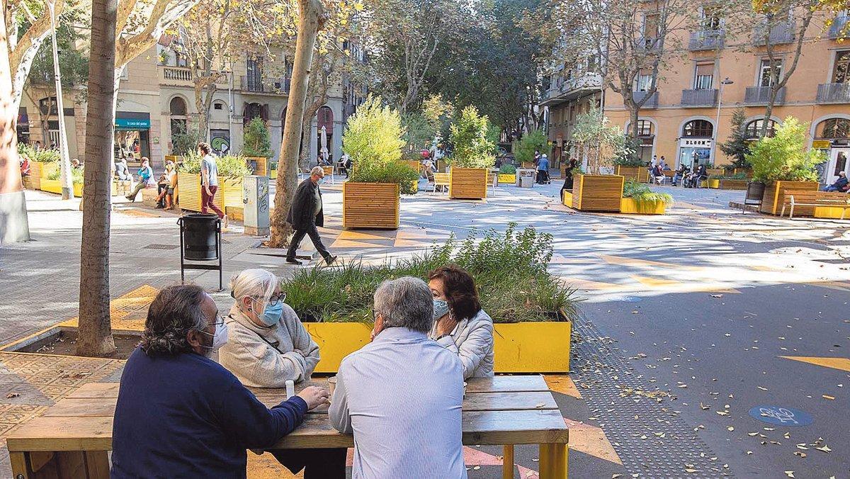 Ciudadanos conversando sentados en una de las mesas de la supermanzana de Sant Antoni.