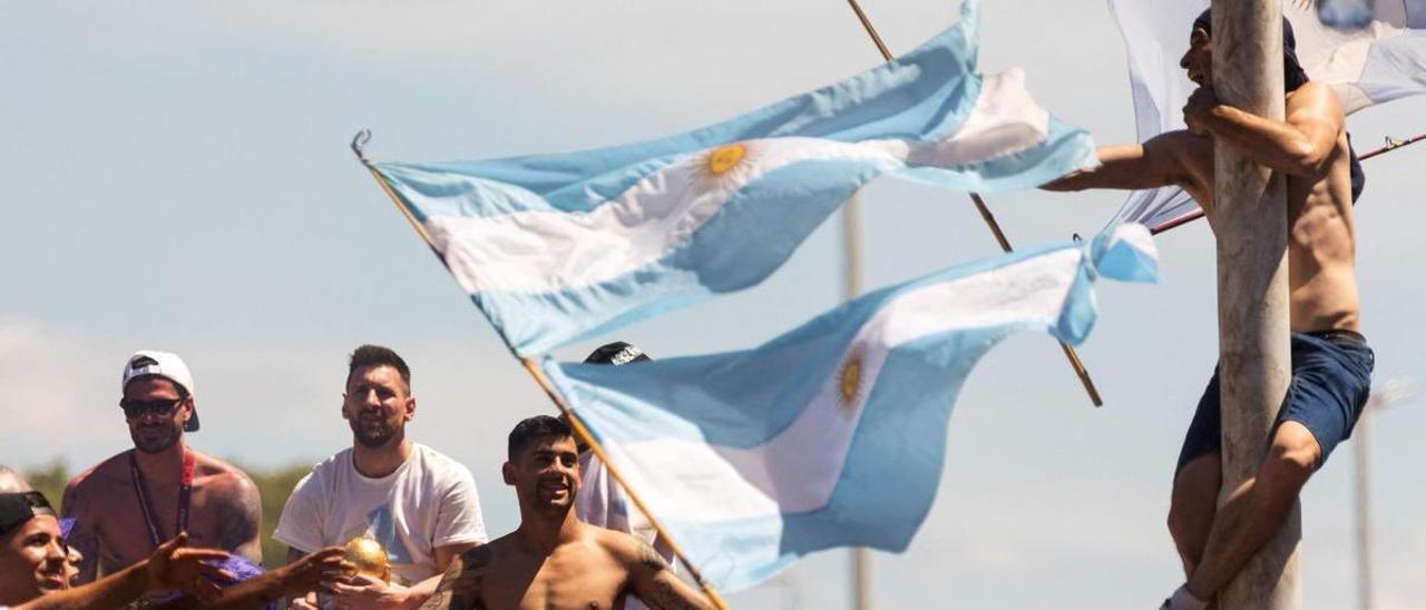 Messi, junto a sus compañeros, en el autobús de la celebración al lado de un seguidor subido en un poste.