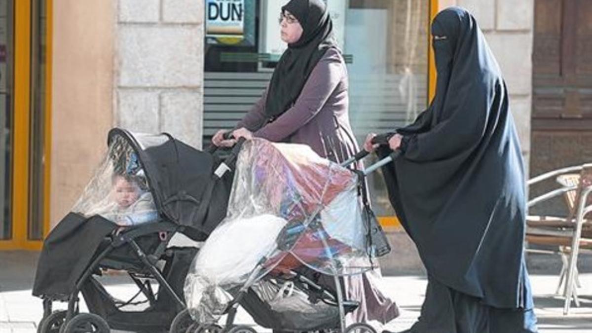 Una mujer con velo integral, a la derecha, pasea con otra que no se cubre el rostro, en Reus.