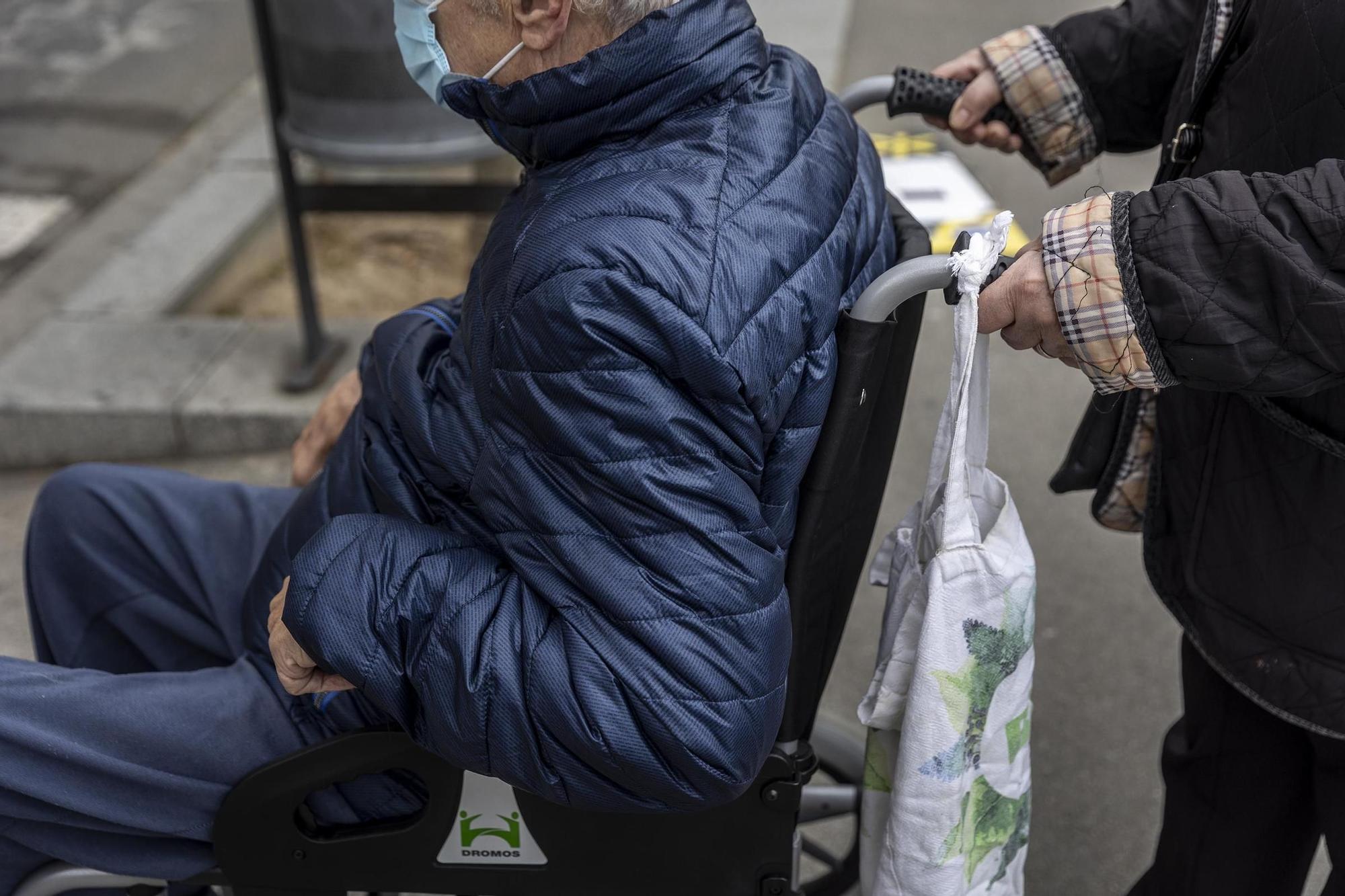 Una persona en silla de ruedas y empujada por una acompañante, en Barcelona.