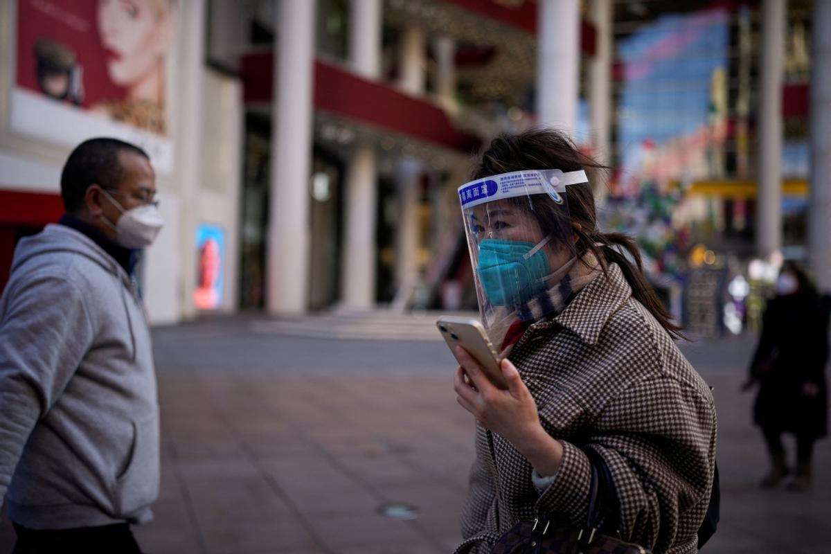 Una mujer con una máscara protectora y un protector facial camina en un distrito comercial mientras China regresa al trabajo a pesar de los continuos brotes de la enfermedad por coronavirus (COVID-19) en Shanghái.