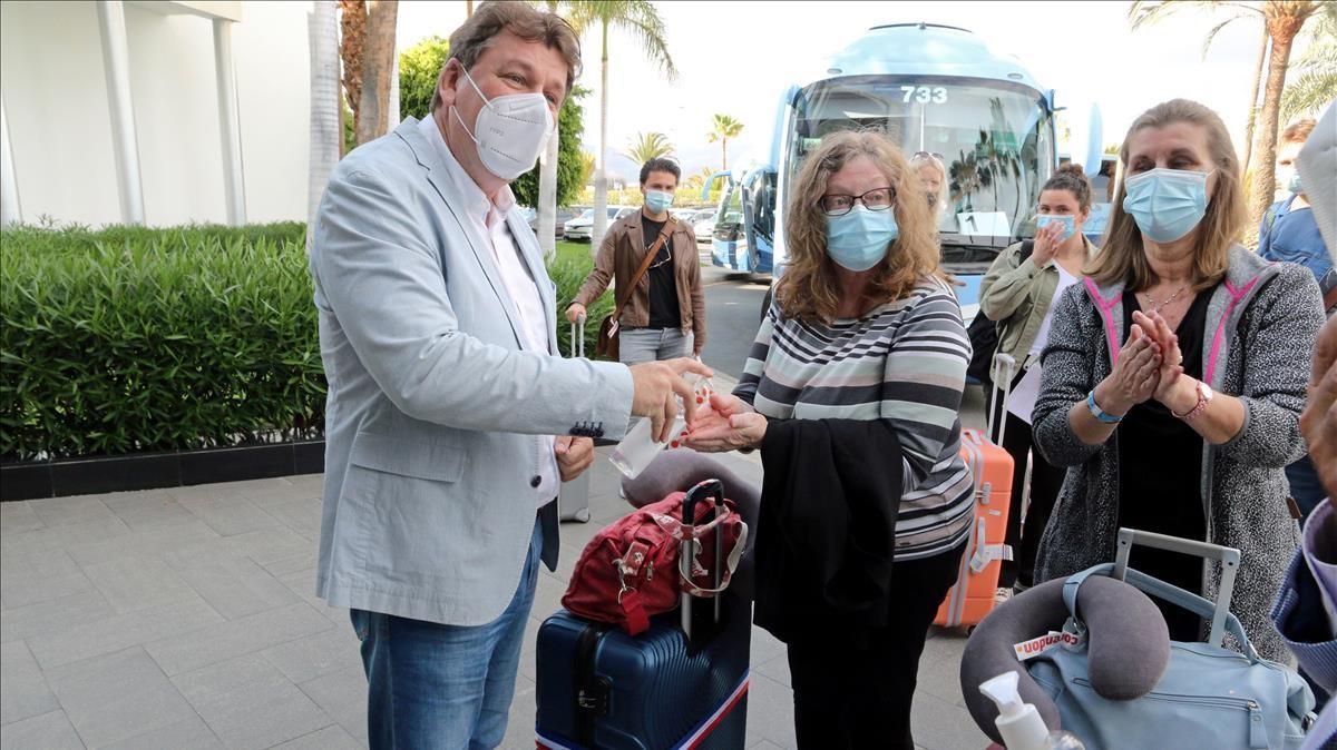 Unas turistas holandesas se frotan las manos con gel hidroalcohólico a su llegada al hotel de Maspalomas.