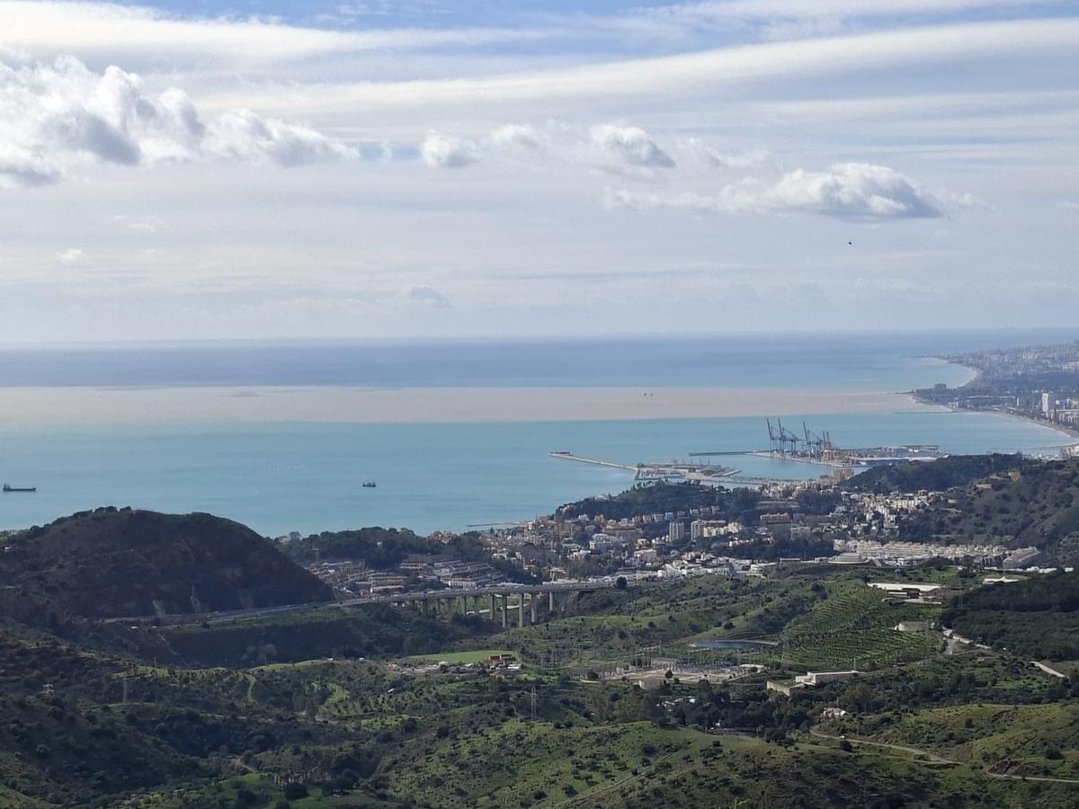 Vista de la capital desde Los Montes, este domingo, en la que se observa una densa franja de barro y lodo en el mar que entra al Mediterráneo procedente del Guadalhorce