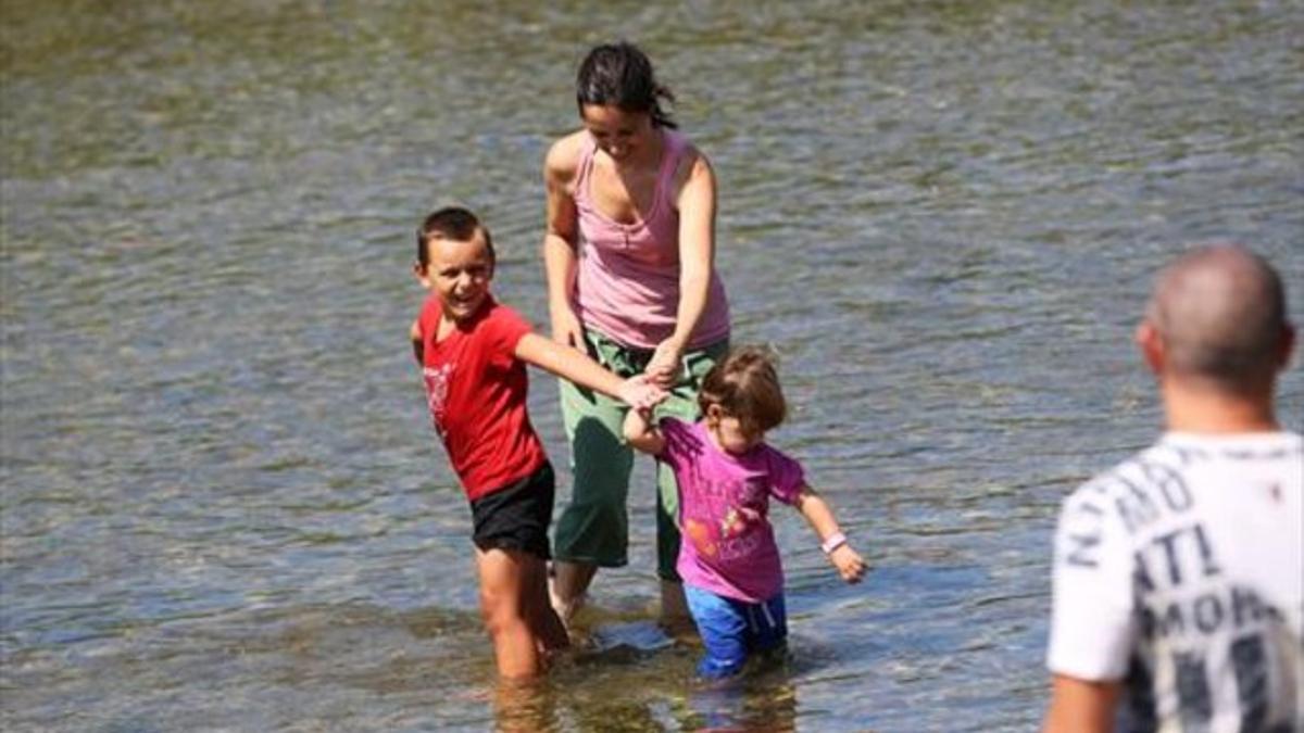 Guillem y Ariadna, de la mano de su madre, Meritxell, se divierten en las aguas del Besòs.