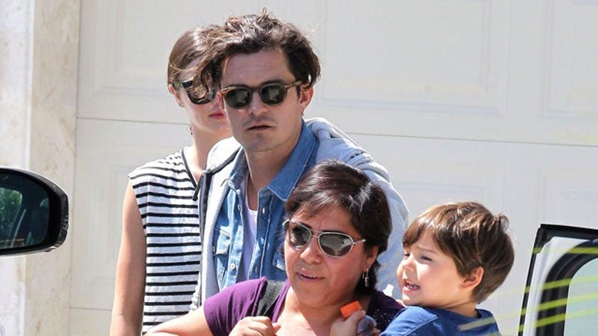 Flynn en brazos de la chica que le cuida y sus padres Orlando Bloom y Miranda Kerr, detrás