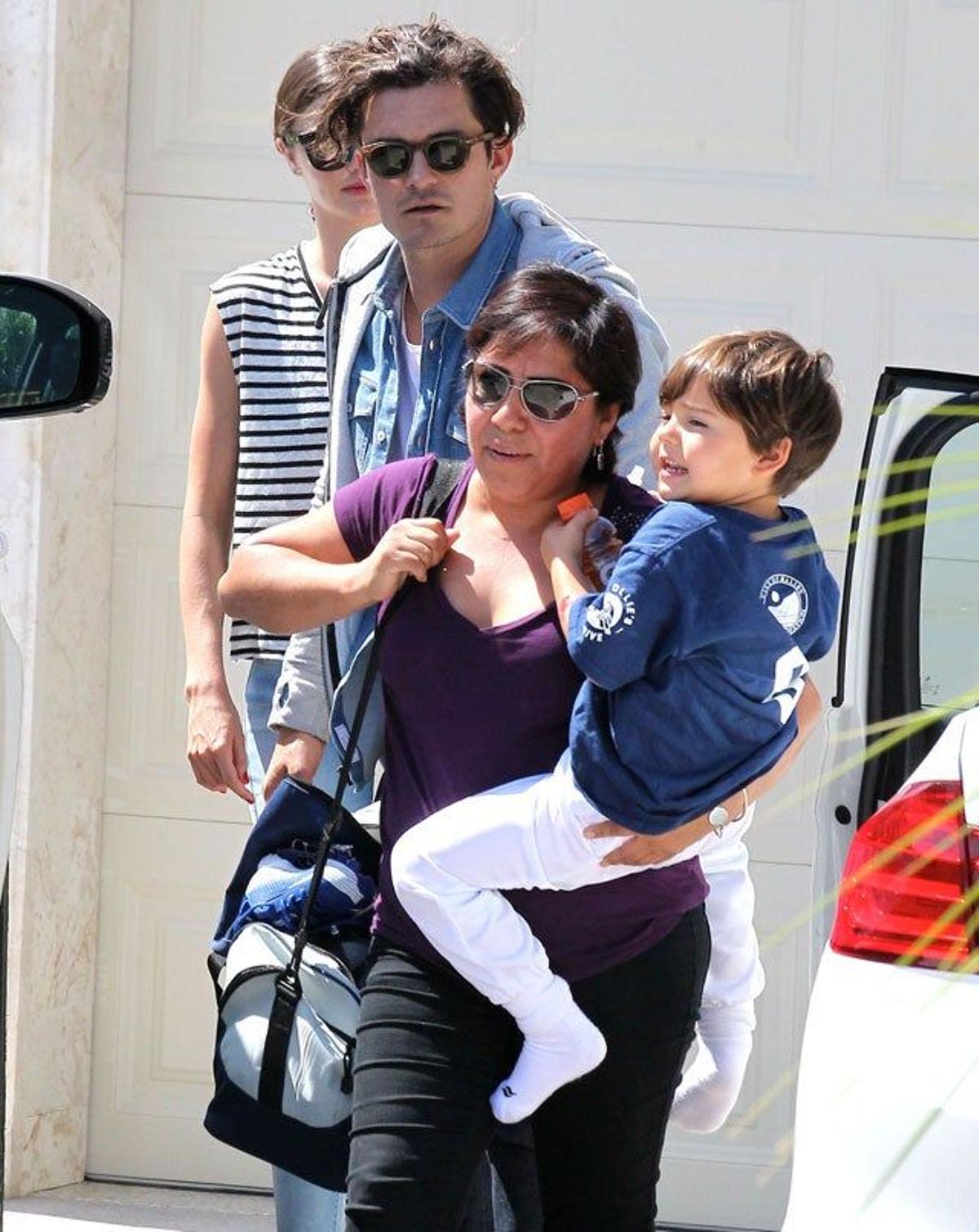 Flynn en brazos de la chica que le cuida y sus padres Orlando Bloom y Miranda Kerr, detrás