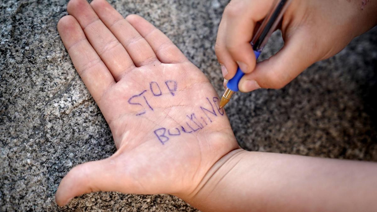 Un niño de primaria escribe en su mano 'stop bullying'.