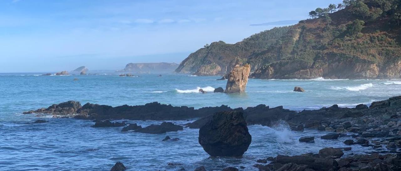 Playa de Aguilar, con la peña del Caballar en medio; al fondo, la isla de la Deva.