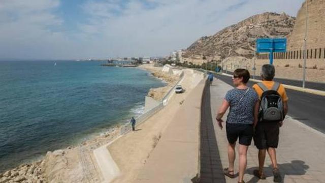 Una pareja camina hacia Alicante por la cantera. Debajo, el sendero