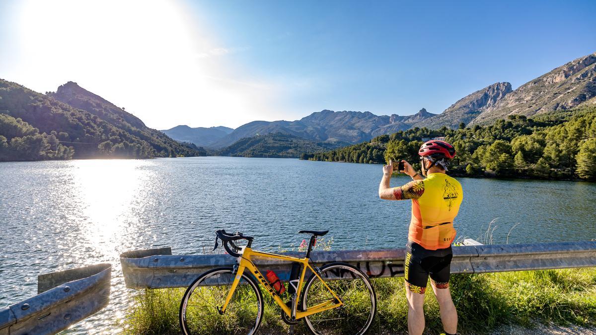 Un ciclista fotografía el embalse de Guadalest, que está al 77% de su capacidad