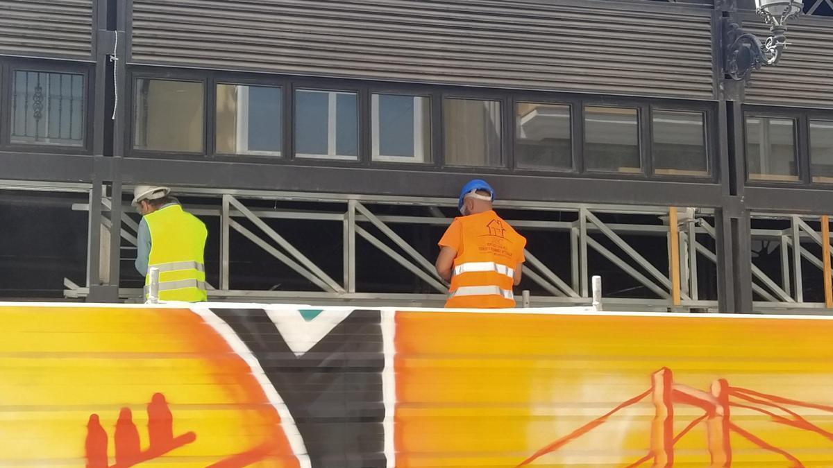 Unos operarios trabajan subidos a un andamio