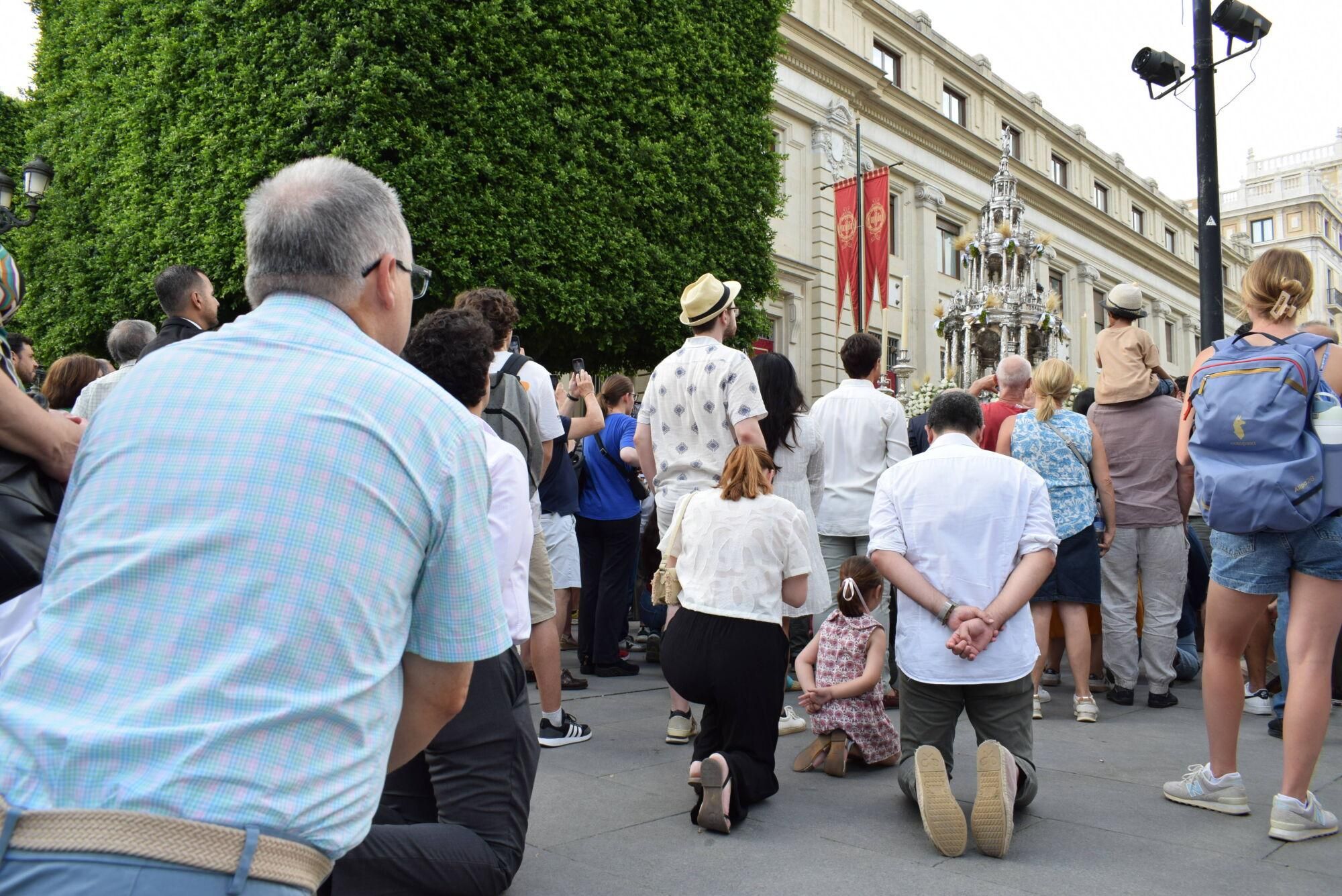 Personas arrodilladas al paso de la Custodia durante el Corpus de Sevilla
