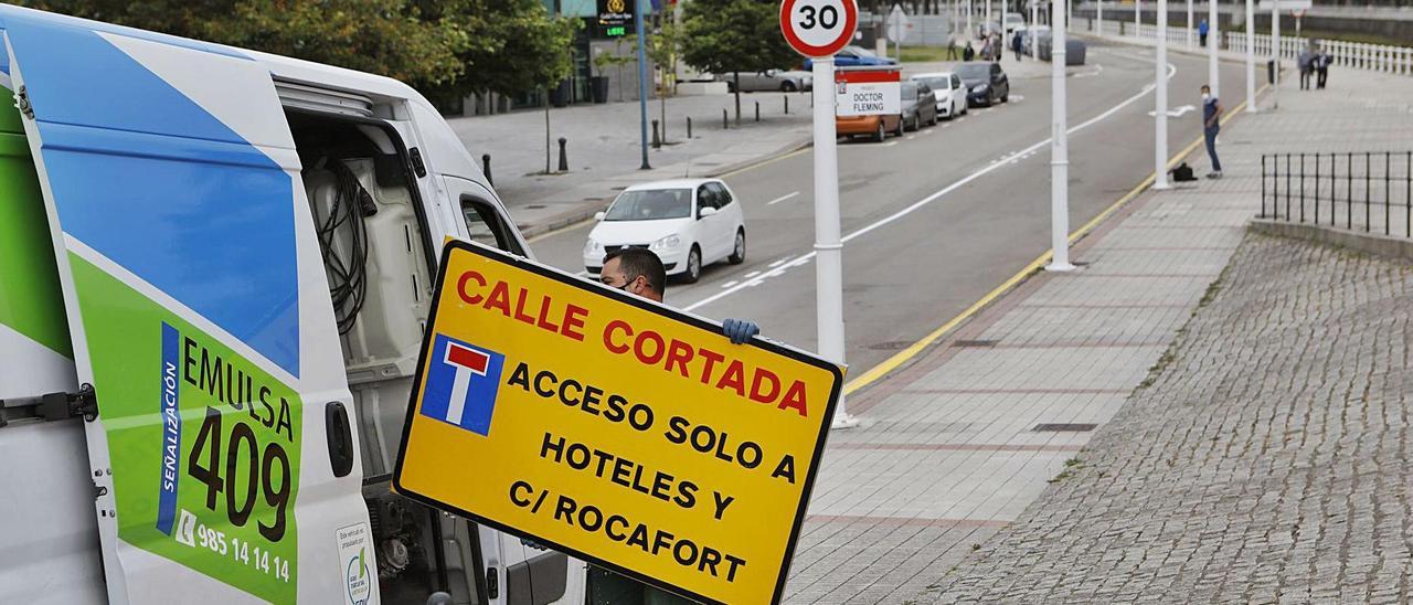 Un operario, ayer, retirando el cartel que informaba del corte de la calle.