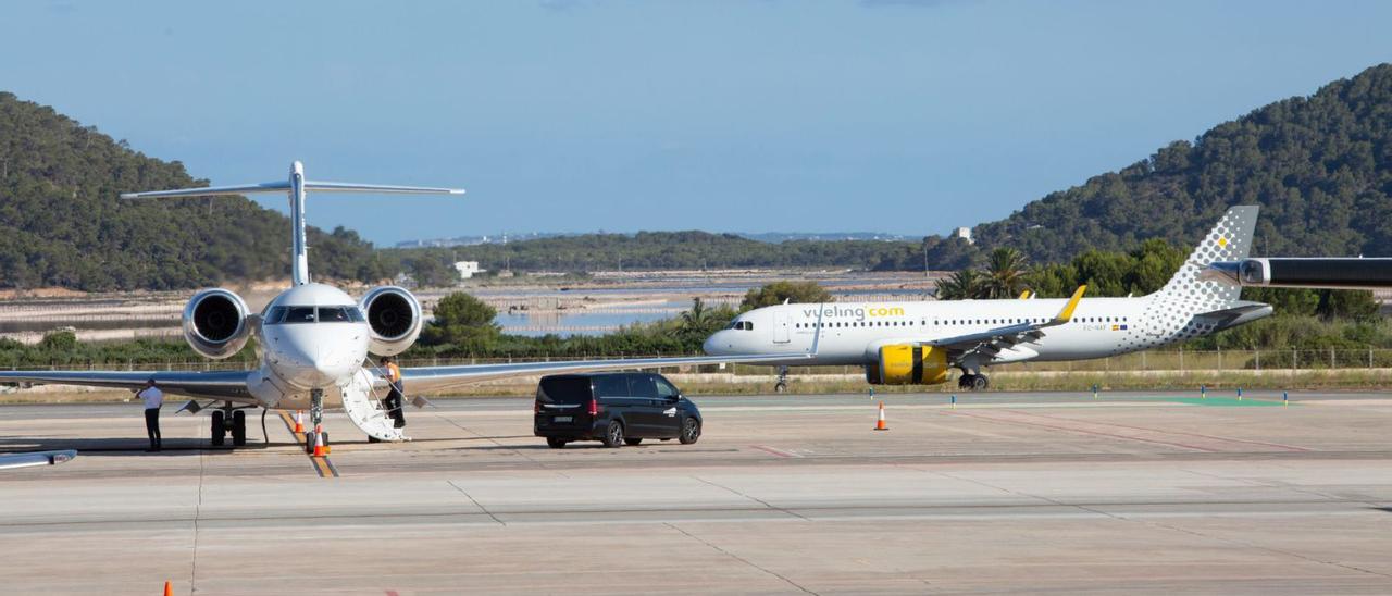 Un avión comercial abandona la pista de aterrizaje rodeando el aparcamiento de los ‘jets’ del aeropuerto de Eivissa. | VICENT MARÍ