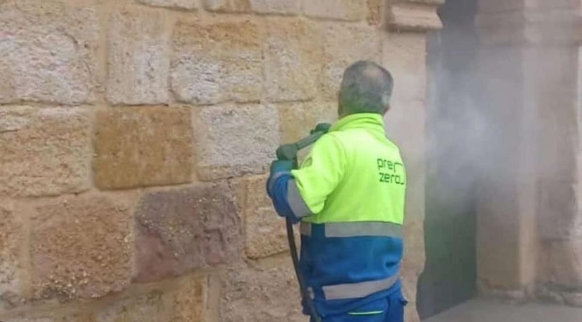 Un trabajador de la concesionaria municipal del servicio de limpieza elimina la pintada.