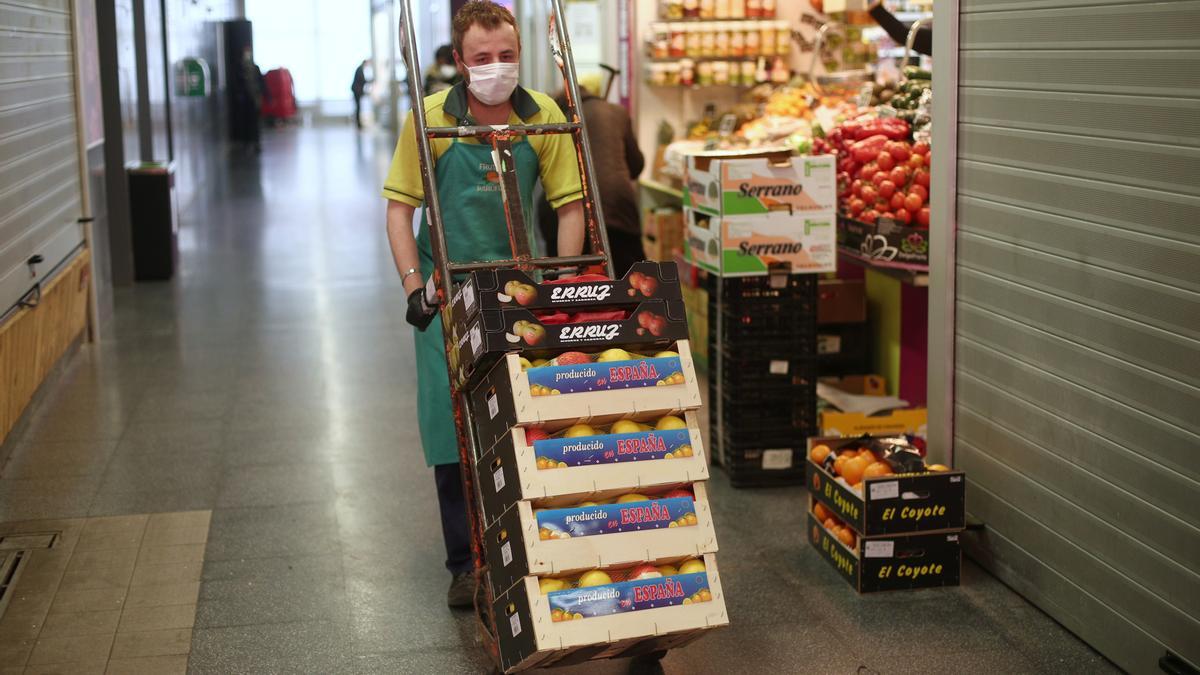 Un trabajador transporta fruta en un mercado.