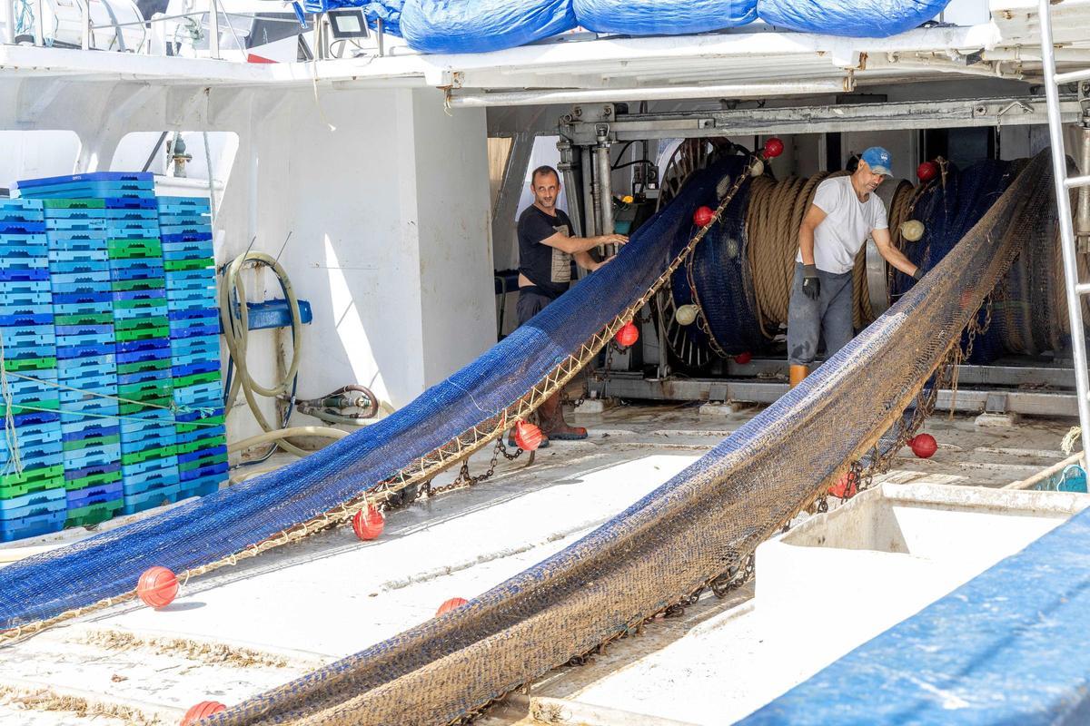 Pescadores recogiendo las redes a bordo de una embarcación.