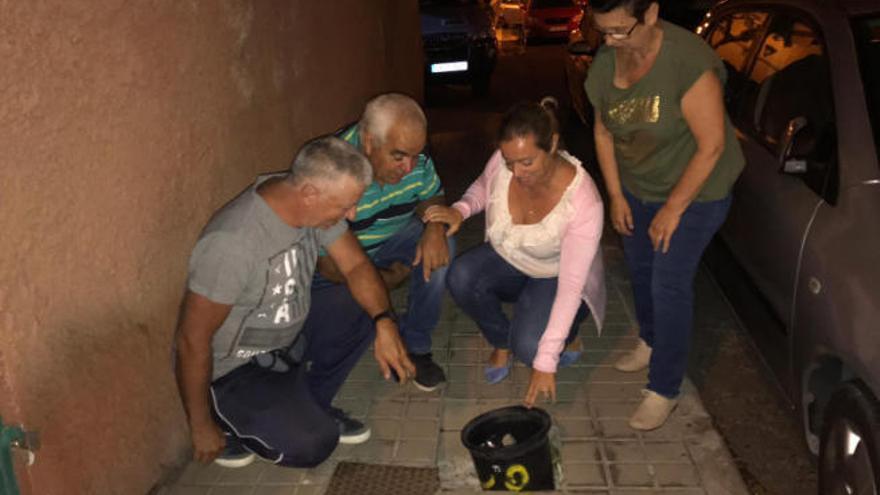 Vecinos de Las Huesas y la portavoz popular, Sonsoles Martín, con uno de los baldes colocados en la acera.