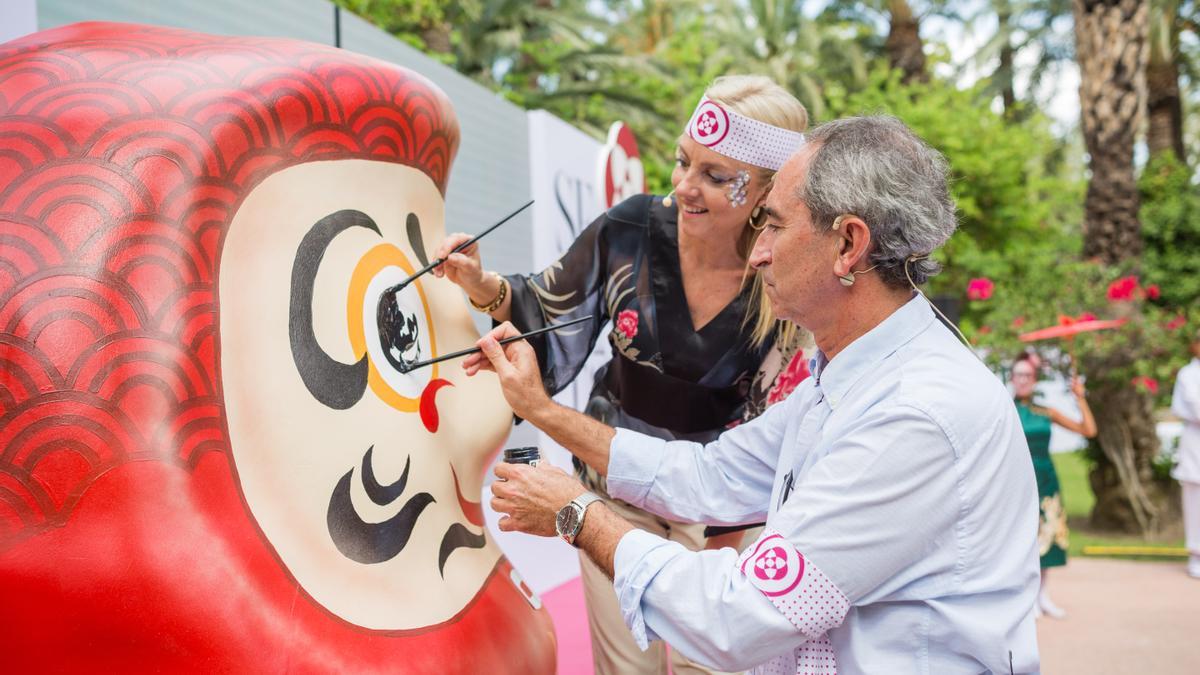 Maite y Pepe Antón pintando uno de los ojos de un daruma gigante, recreado a gran tamaño para la escenografía del evento.