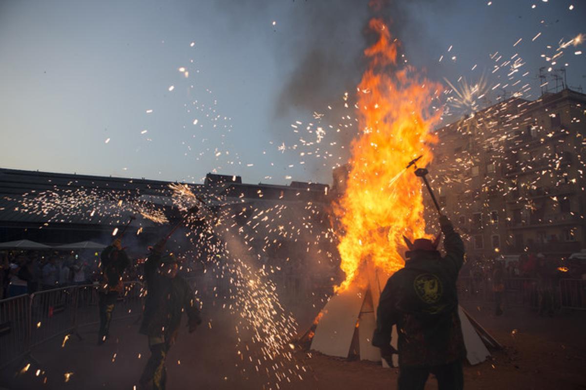 Tres homes ballen al voltant d’una foguera a la plaça de la Font, al costat del mercat de la Barceloneta