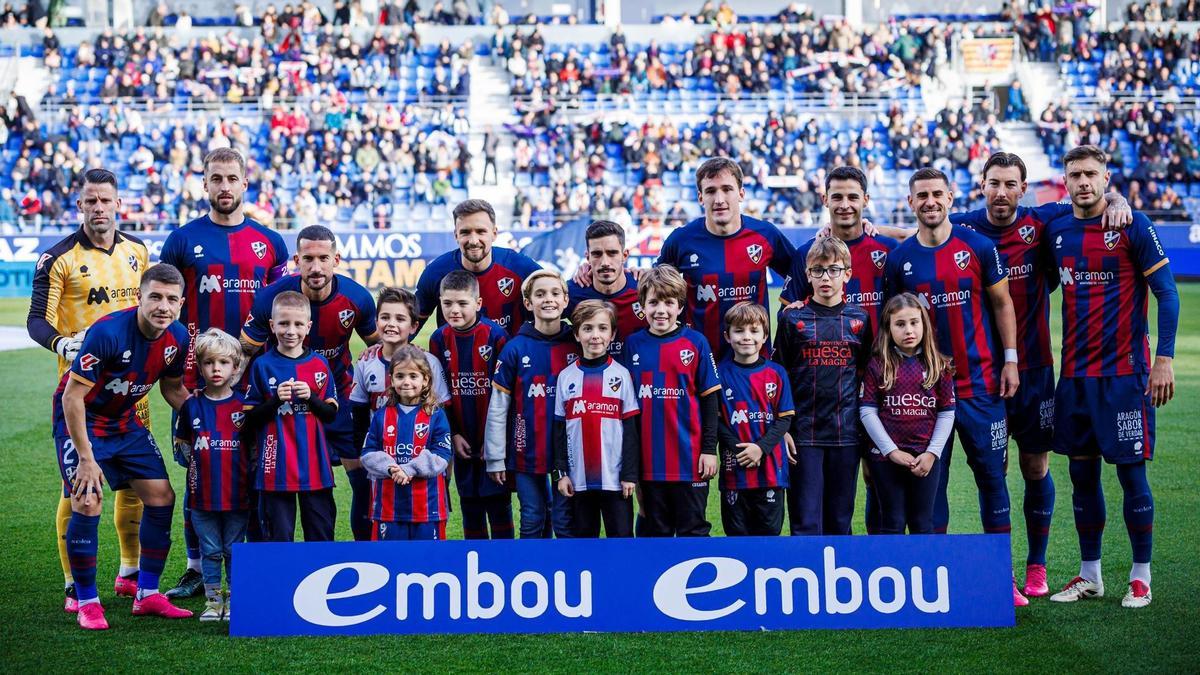 Once inicial del Huesca, junto a varios niños y niñas azulgrana, en su partido de este curso ante el Sporting.
