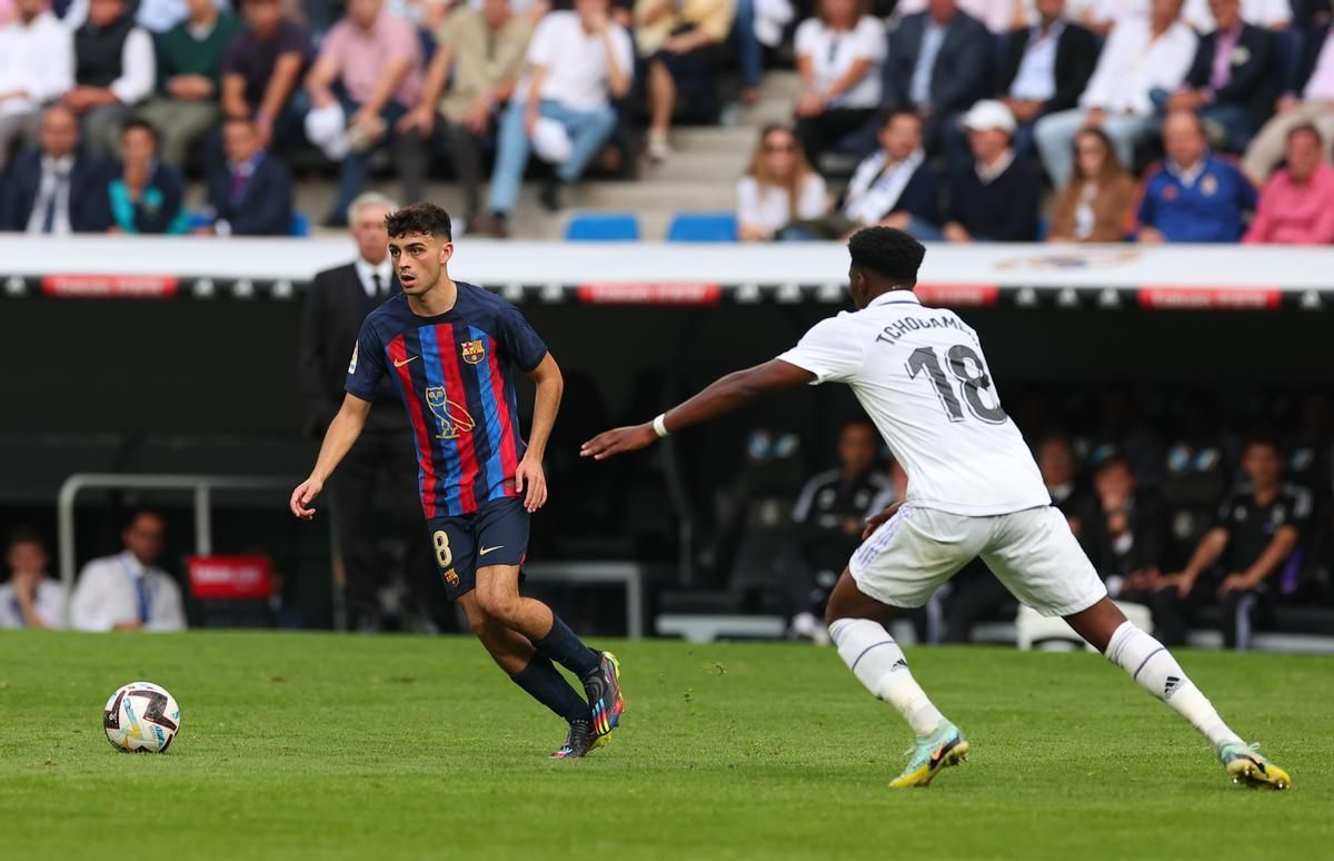 Pedri, jugador del Barça, conduce un balón ante el madridista Tchouaméni en el Clásico disputado en el Bernabéu.