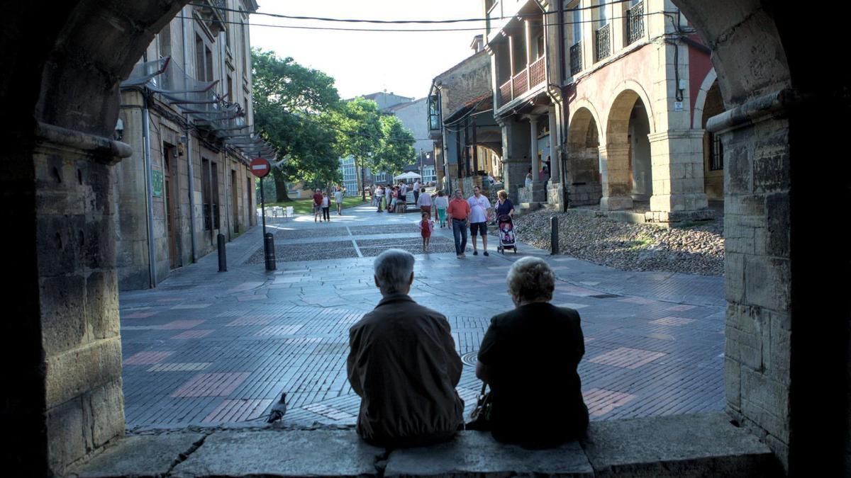 Una pareja mayor, sentada en la calle de Galiana de Avilés.