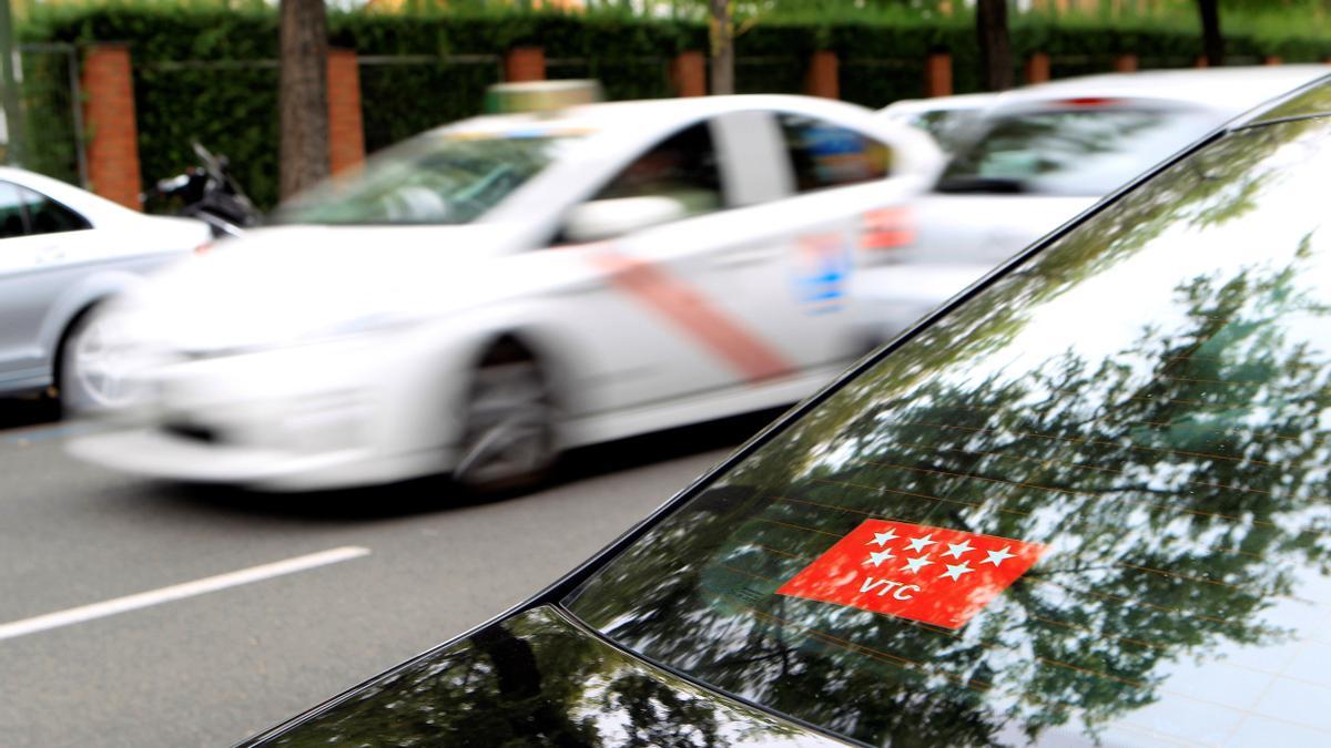 Un taxi pasa frente a un vehículo VTC, en una calle del centro de Madrid.