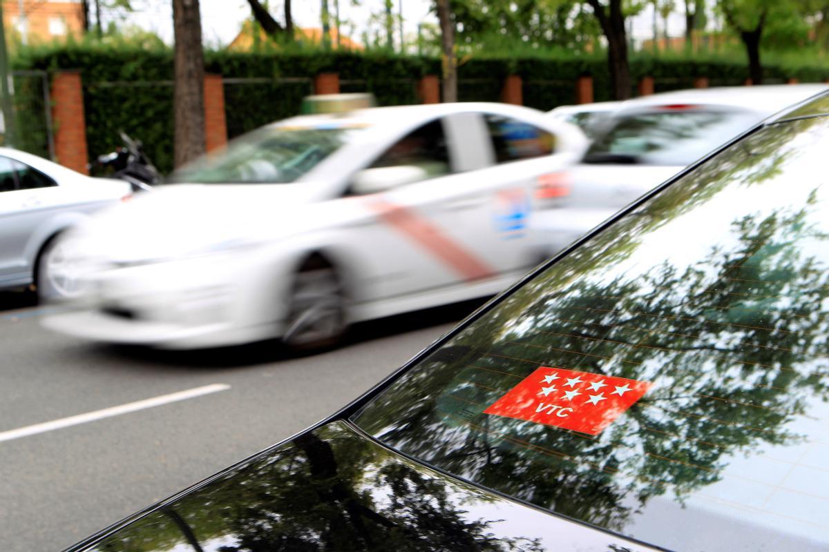 Un taxi pasa frente a un vehículo VTC, en una calle del centro de Madrid. 