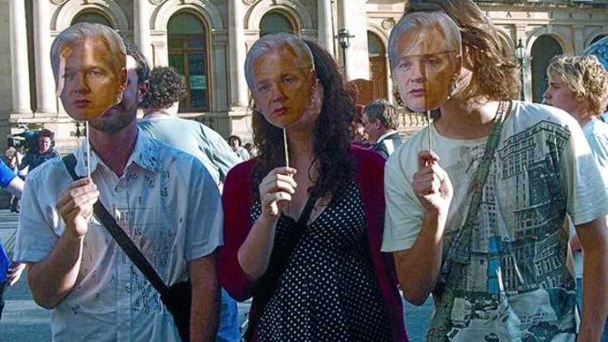 Tres manifestantes sostienen caretas de Julian Assange, en una protesta a su favor en Brisbane (Australia).