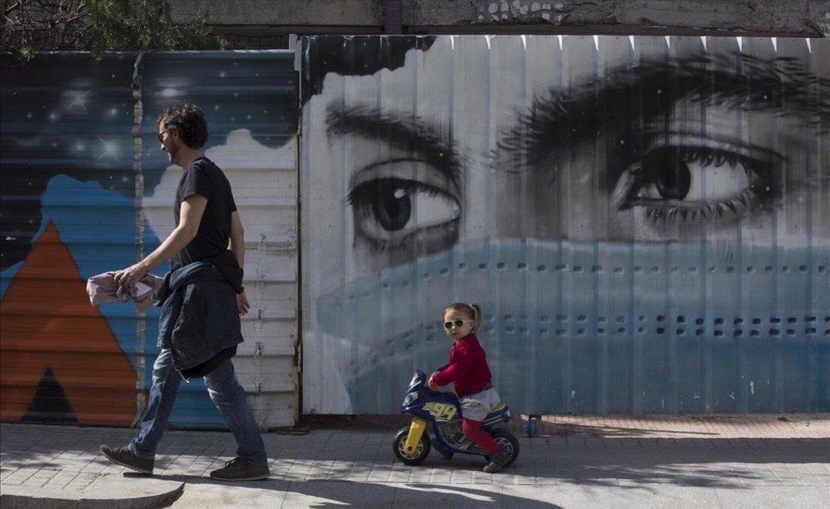 Grafiti de una mujer con mascarilla en una calle del barrio de la Bonanova, en Barcelona.