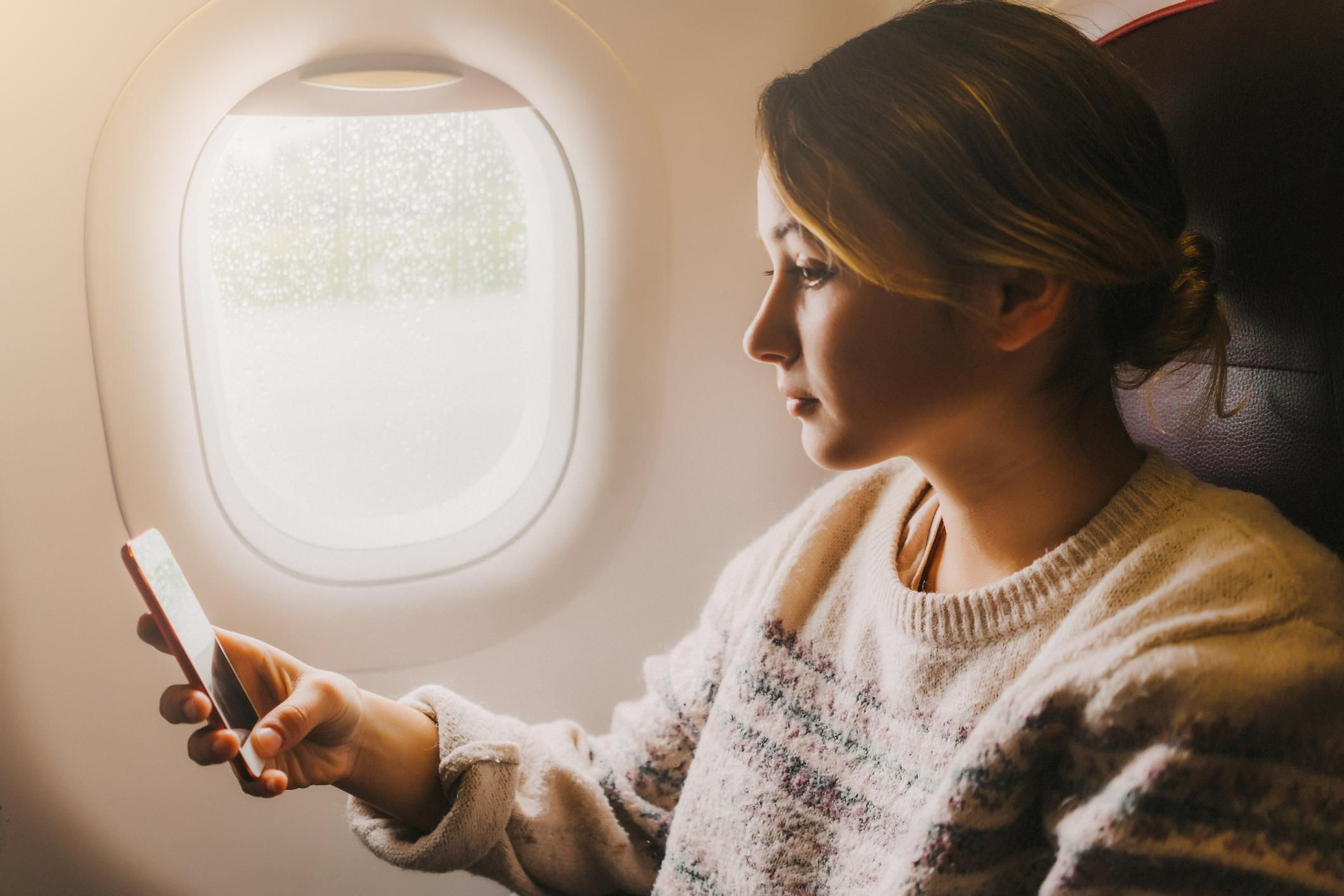 Mujer en un avión con un smartphone.