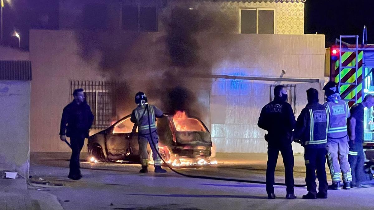 Bomberos y Policía Local de San Javier tratando de extinguir las llamas que envuelven al coche.