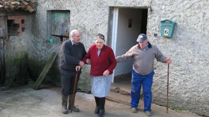 Los dos hermanos, junto a su madre, en la entrada de su vivienda de Foxado, en el municipio de Curtis. / l. o.