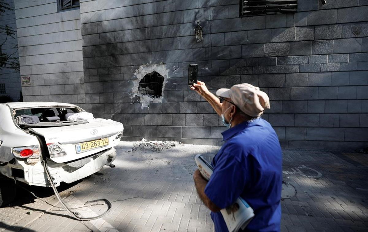 Un hombre israelí saca una foto con su móvil de un agujero provocado en un edificio residencial de Ashkelon por un cohete lanzado desde la Franja de Gaza.