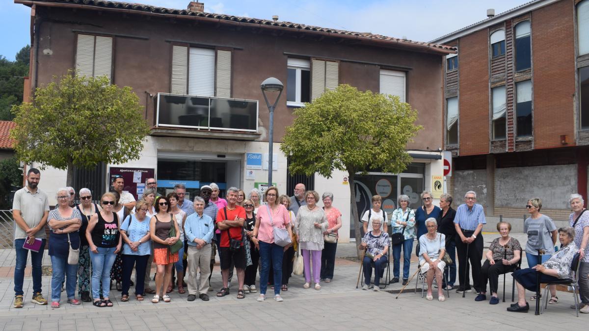 L'alcalde d'Olvan, Sebastià Prat (esquerra), amb una tretena de veïns i veïnes davant del consultori de Cal Rosal