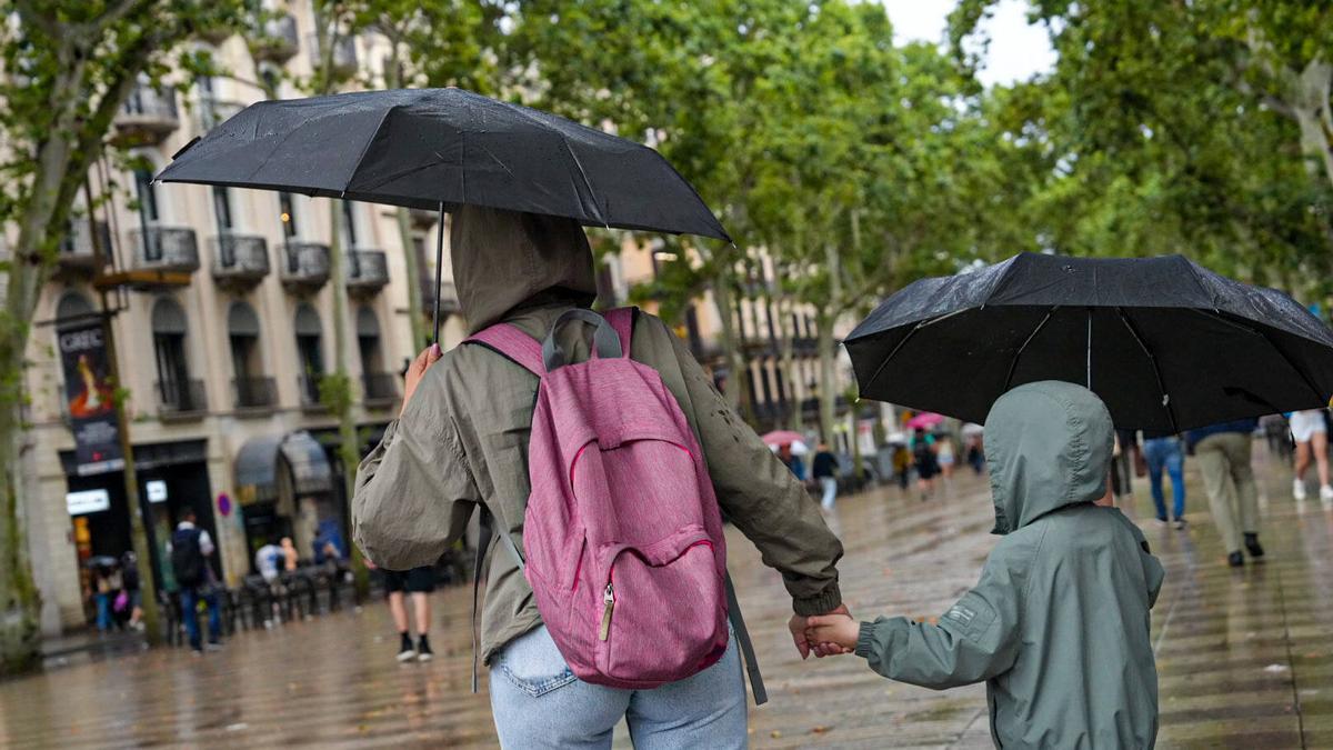 Personas con paraguas en el centro de Barcelona, este lunes.