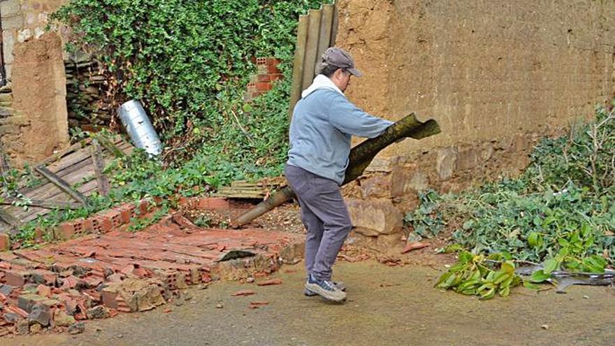 Una operaria municipal recogiendo parte de uralita arrancada por el tornado y detrás un muro caído. | E. P.