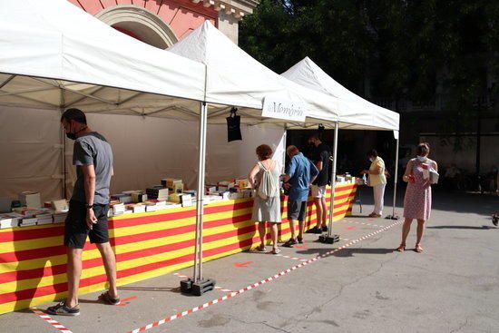 La plaça de la Vila de Gràcia de Barcelona amb la parada d'una llibreria durant el Sant Jordi d'estiu.