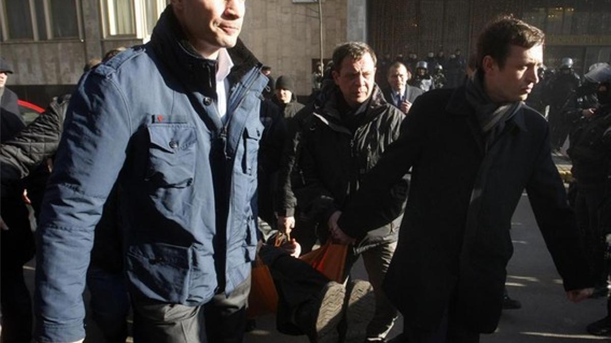 Vitali Klitschkó (izquierda) y otros activistas antigubernamentales trasladan a una persona herida