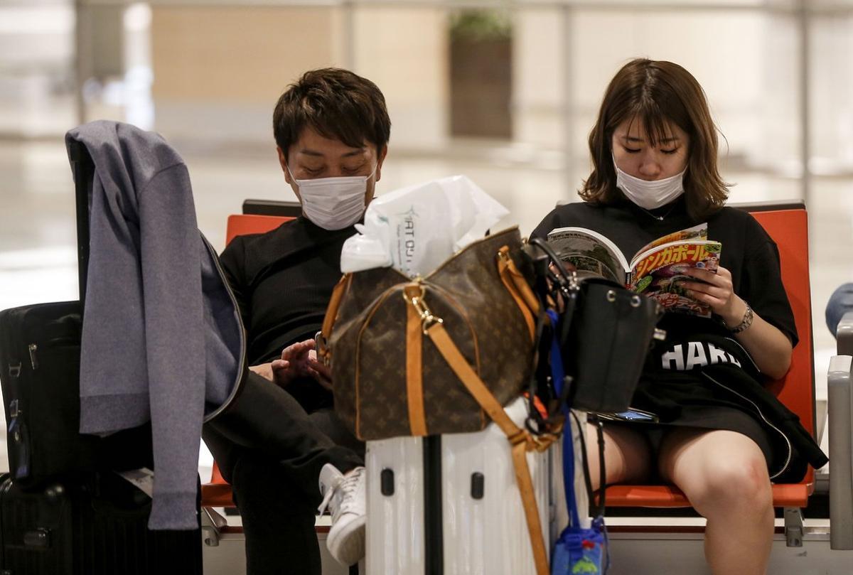 Singapore (Singapore), 09/02/2020.- A couple wear protective masks at the arrival hall of Changi Airport in Singapore, 09 February 2020. Singapore’s Ministry of Health has reported 40 cases of the novel coronavirus (2019-nCoV). The Ministry of Health has raised its Disease Outbreak Response System Condition (DORSCON) level from yellow to orange, meaning that additional precautions will be taken such as increased temperature screening and the cancellation of group activities in schools and the community. (Singapur, Singapur) EFE/EPA/WALLACE WOON