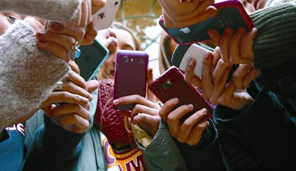 Unes adolescents dun centre de Barcelona consulten  els seus mòbils.