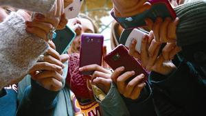 Unes adolescents dun centre de Barcelona consulten  els seus mòbils.