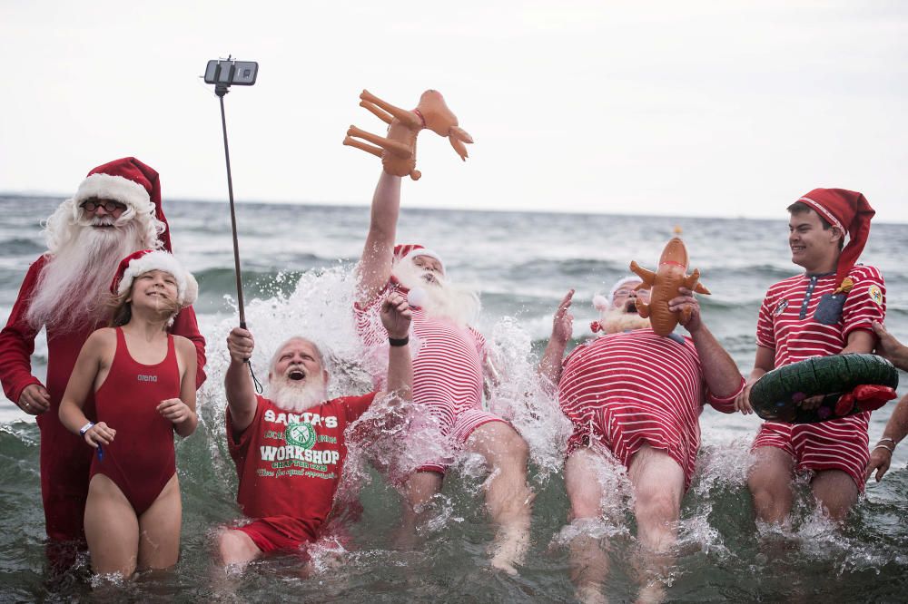 Gente vestida como Santa Claus se baña en el mar mientras participan en el Congreso Mundial de Santa Claus, un evento anual que se celebra cada verano en el parque de atracciones Dyrehavsbakken, en Copenhague, Dinamarca.