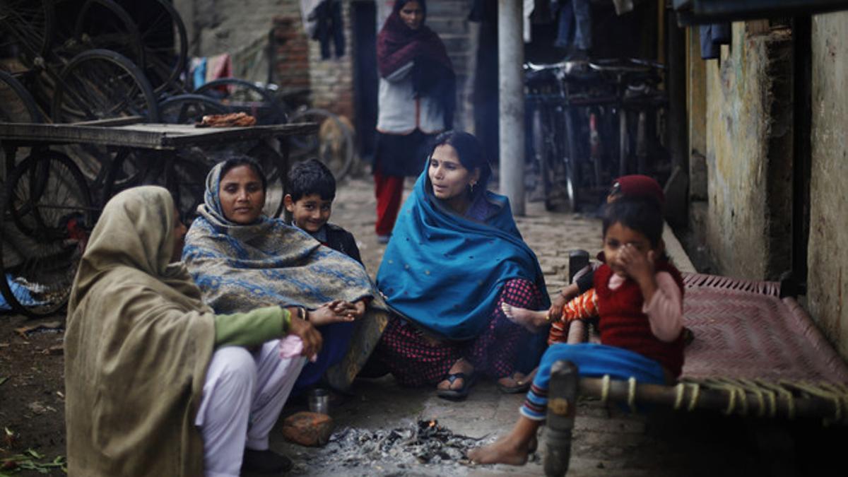 Mujeres y niños se calientan alrededor de una hoguera, en Nueva Delhi.