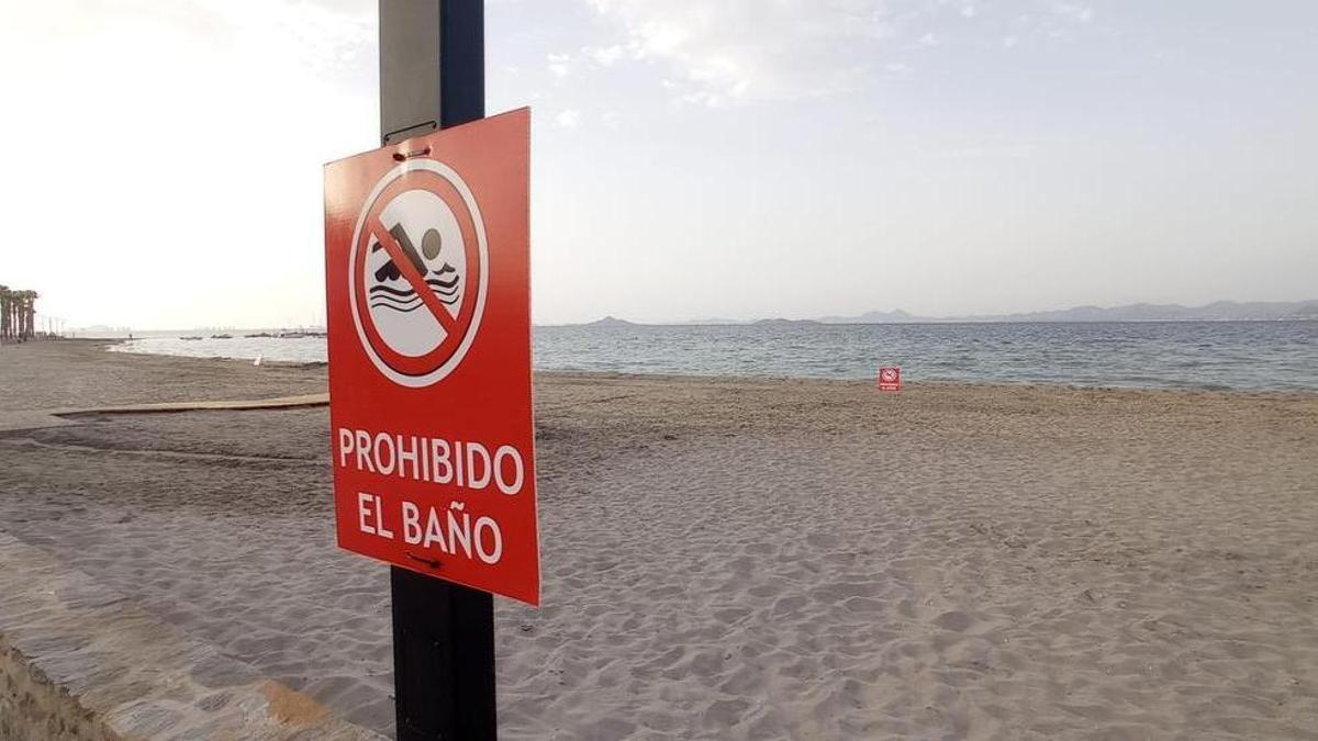 Playa con cartel que prohíbe el baño