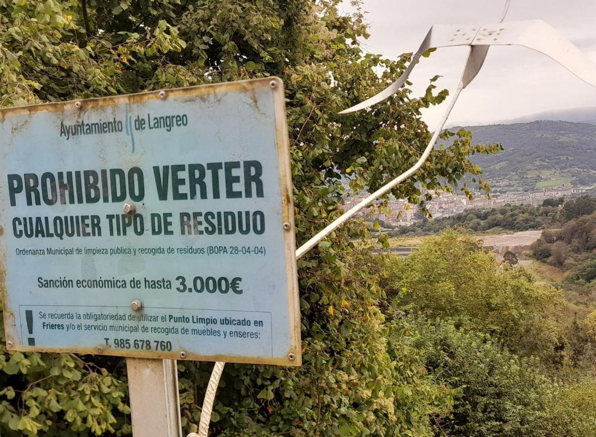 Cartel en Cuturrasu que prohíbe verter basuras, con la escombrera al fondo. | L. M. D.