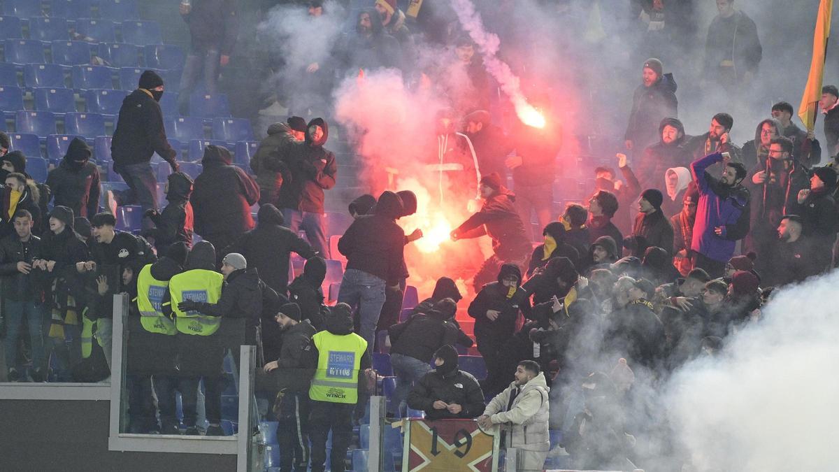 Aficionados del Roma intentan apagar bengalas que se lanzaron mutuamente con los del Lazio el pasado miércoles.