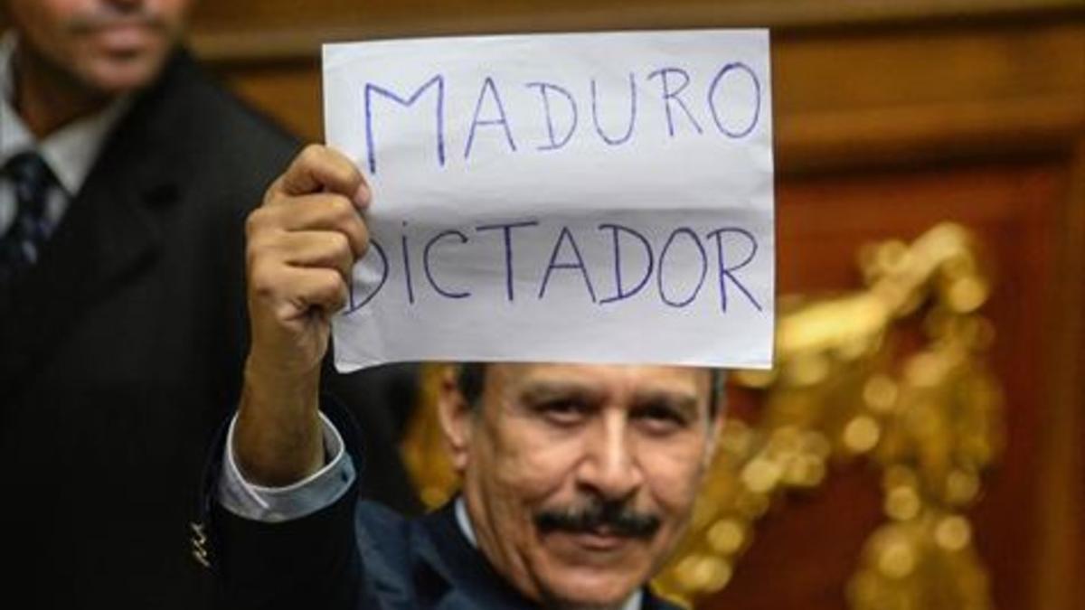 Un diputado de la oposición muestra un cartel contra Maduro.